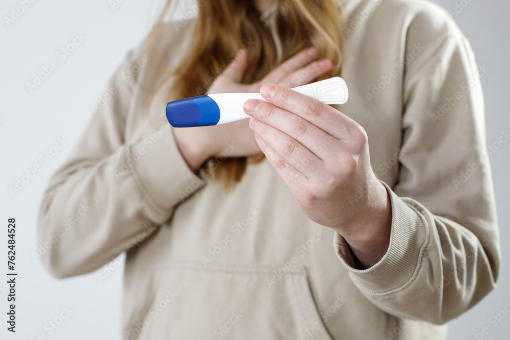 Close-up shot of a woman looking at a pregnancy test. She checks the pregnancy exam. Details of a girl's hand holding a pregnancy test. Shallow depth of field with focus on pregnancy test. Close-up shot of a woman looking at a pregnancy test. She checks the pregnancy exam. Details of a girl's hand holding a pregnancy test. Shallow depth of field with focus on pregnancy test.