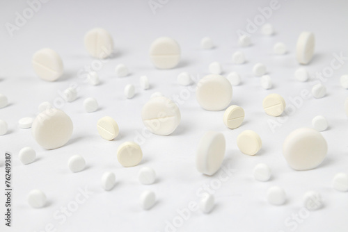 Lot of white round pills on the bright surface. Different tipes of drugs photo