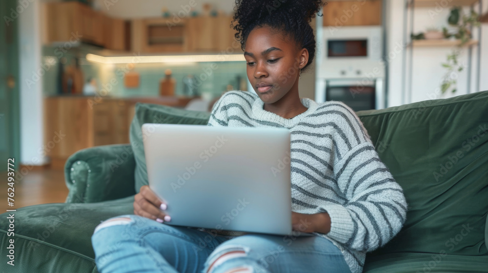 A focused individual works on a laptop while sitting cross-legged on a green couch, indicative of the modern telecommuting lifestyle. A focused individual works on a laptop while sitting cross-legged on a green couch, indicative of the modern telecommuting lifestyle.