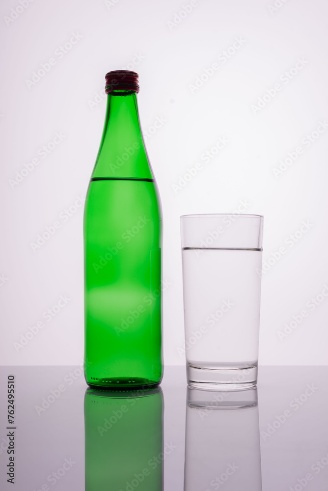 green mineral water bottle with glass on white background