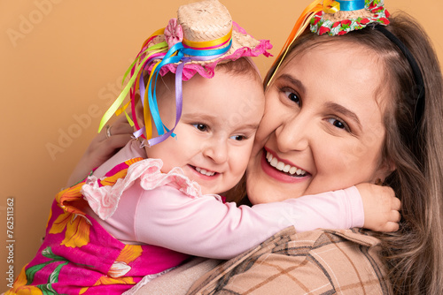 happy mother and daughter to Festa Junina: party in Brazil in beige colors. hugging each other 