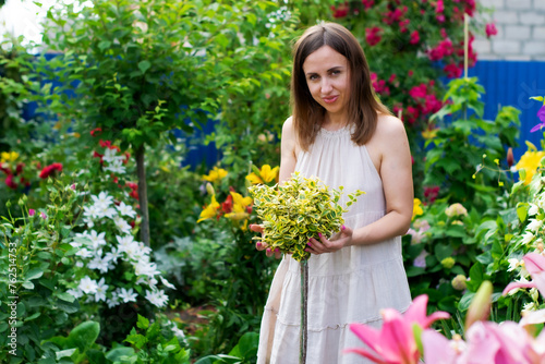 A woman in a garden looking at a decorative euonymus.	