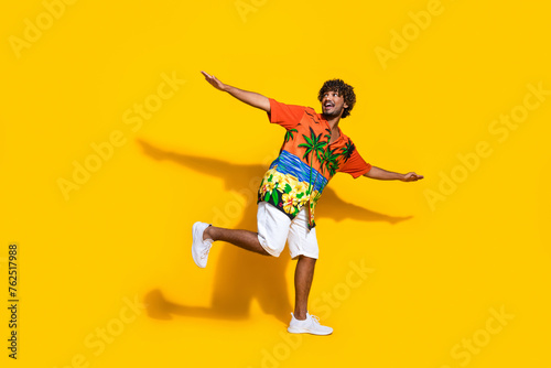 Fototapeta Naklejka Na Ścianę i Meble -  Full size photo of positive man dressed print shirt hold palms like wings look at promo empty space isolated on yellow color background