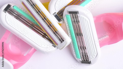 Close up of pink and yellow disposable razors on white table. Macro shoot of the razor blade, rotation. photo