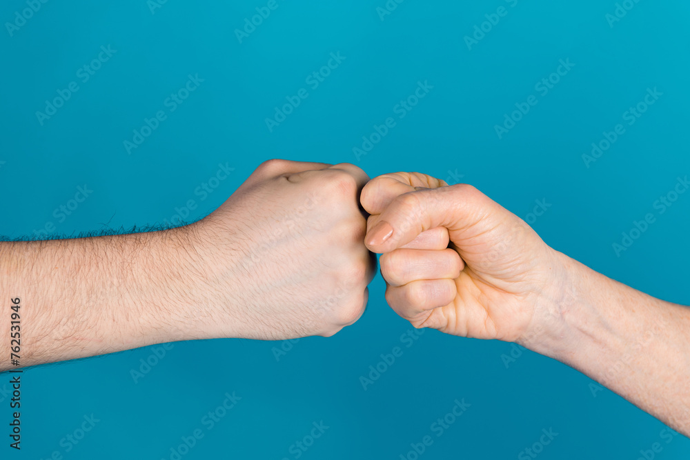 Photo of two female male arms bumping fists having working conflict isolated blue color background Photo of two female male arms bumping fists having working conflict isolated blue color background