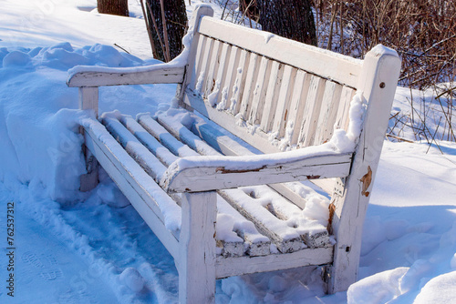 an old wooden bench in a snow-covered park