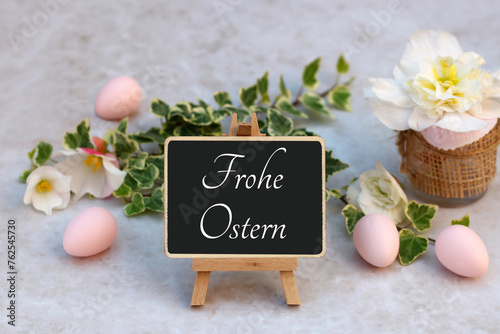 Grußkarte Frohe Ostern. Frohe Ostern auf Schiefertafel mit Blumen und Ostereiern.