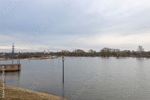 flooded park with paths and sidewalks, early spring flood, river overflowing its banks, environmental pollution, ecology © Sergei