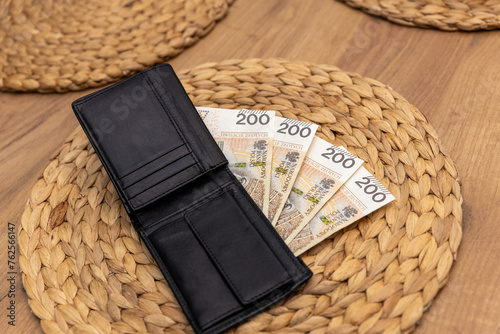 800 złotych rozłożonych na portfelu, obok smoczka, reprezentuje koncepcję pomocy państwa w formie finansowej dla młodych rodziców oraz ulg podatkowych dla rodziców dziecka.