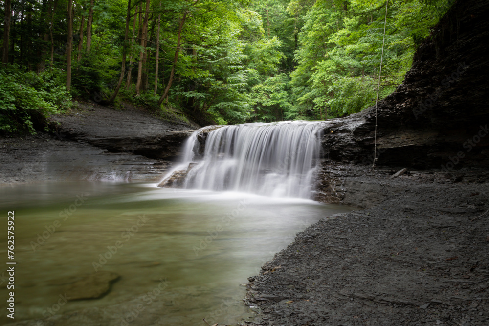 Obraz premium Smooth motion in the water of a waterfall in a green forest 