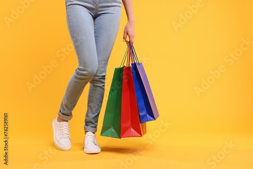 Woman with shopping bags on yellow background, closeup. Space for text