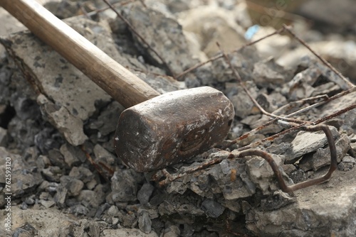 Sledgehammer on pile of broken stones outdoors, closeup