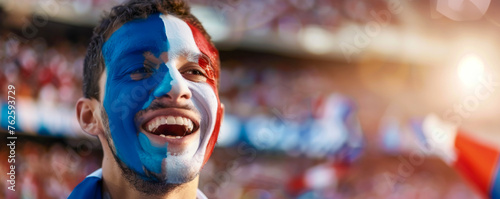 Happy French male supporter with face painted in French flag displaying the country's national colours: blue, white, and red, French male fan at a sports event such as football or rugby match photo