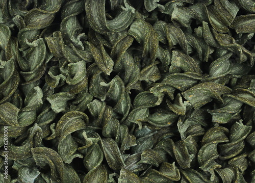 Uncooked fusilli spirulina, organic dry pasta background, top view