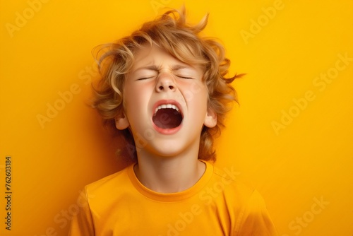 Young boy standing in front of yellow wall, looking up with closed eyes, surprised confusion, he heard or seen something unexpected or terrible. He very emotional expression sings songs