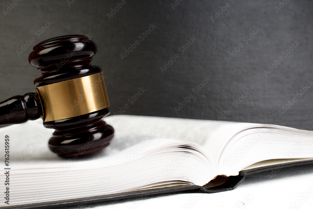 Law concept - Open law book with a wooden judges gavel on table in a courtroom or law enforcement office isolated on white table. Copy space for text. Law concept - Open law book with a wooden judges gavel on table in a courtroom or law enforcement office isolated on white table. Copy space for text.