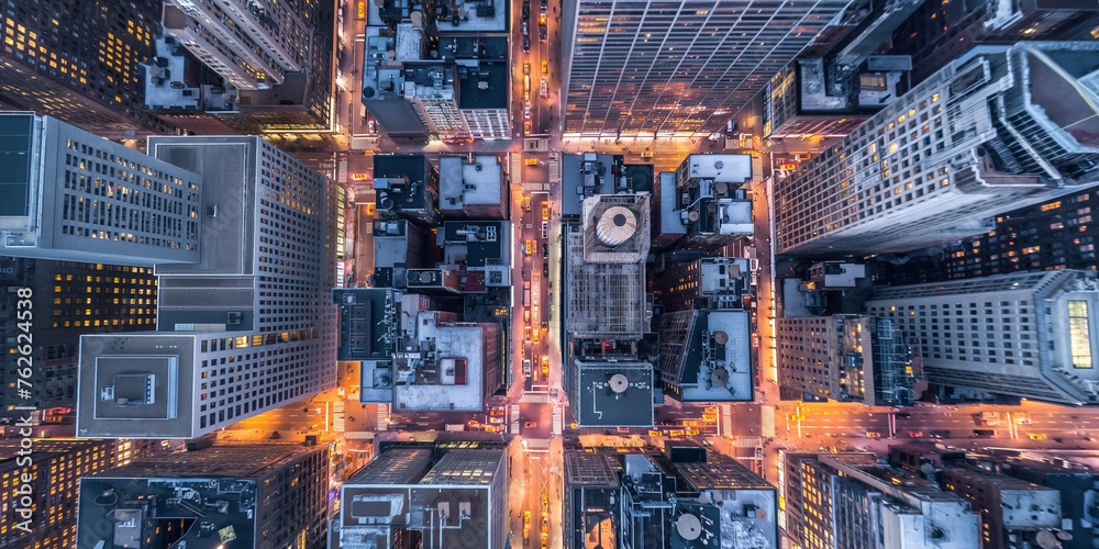 A top-down night-time view of bustling city streets, glowing with the lights of traffic and skyscrapers