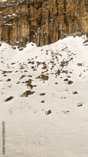 Vertical close up drone shot of a, steep, snow covered mountain - Greenland