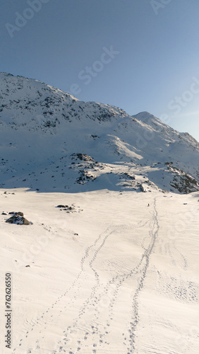 Vertical shot of cold snow covered mountains, with a path trail towards the camera  - Greenland