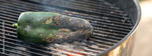 Charring a green chili pepper on a grill outside © Cam