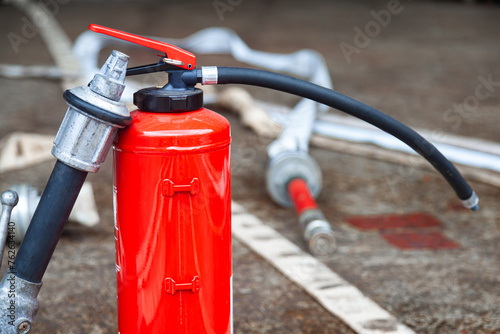 Red fire extinguisher cylinder with unwound fire hoses. photo