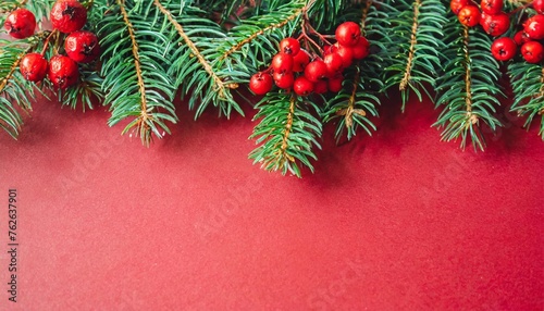 beautiful celebratory christmas red background with fir or pine branches and rowan berries new year s holidays top view with copy space