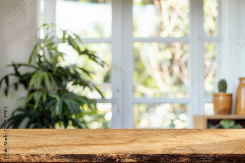 Wooden table top with blurred green plants and garden view through the window. High quality photo © oksa_studio