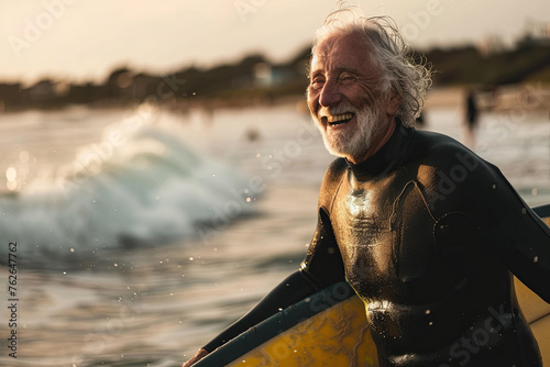 A happy elderly surfer in a wetsuit rests on his board in the calm sea, soaking in the beauty of the sunset surf. © Maria