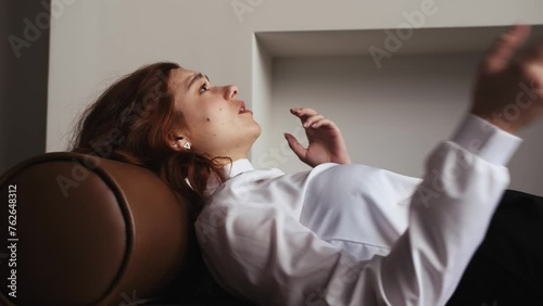 Therapy session: Young caucasian beautiful woman lying on sofa, waving hands while emotionally talking to her doctor psychologist. psychologist listening his patient concept 