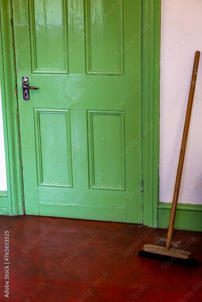 Dust sweeping, Image shows a pile of dust swept up into a pile using the wooden broom or brush on a dark red vinyl floor with a lime green door and cream wall background Dust sweeping, Image shows a pile of dust swept up into a pile using the wooden broom or brush on a dark red vinyl floor with a lime green door and cream wall background
