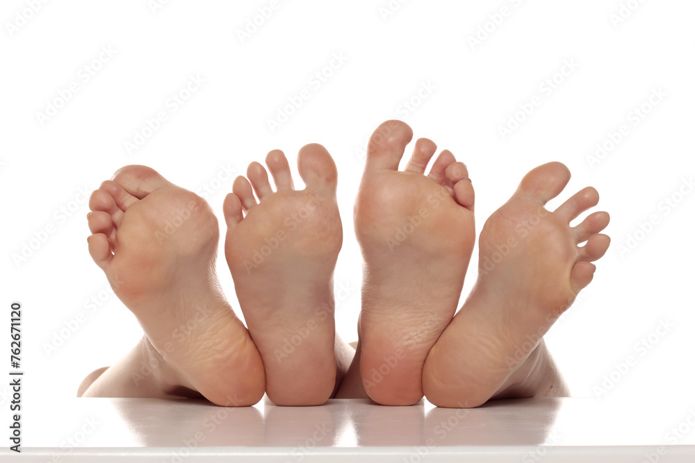 Two pairs od a beautiful well-groomed women's sole feet close-up on a white isolated studio background, The concept of foot skin care. Two pairs od a beautiful well-groomed women's sole feet close-up on a white isolated studio background, The concept of foot skin care.