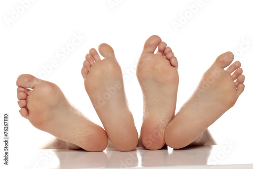 Two pairs od a beautiful well-groomed women's sole feet close-up on a white isolated studio background, The concept of foot skin care