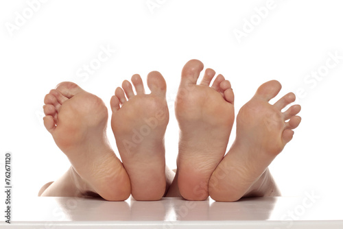 Two pairs od a beautiful well-groomed women's sole feet close-up on a white isolated studio background, The concept of foot skin care.