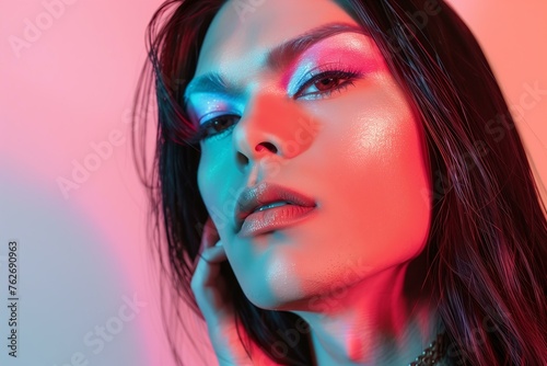 trans woman with beautiful makeup, long hair, on a pink and blue background, studio shot