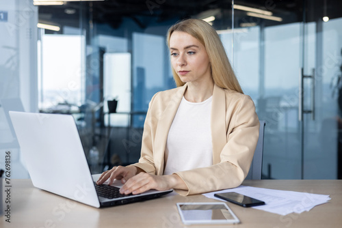 Focused businesswoman working on laptop in modern office