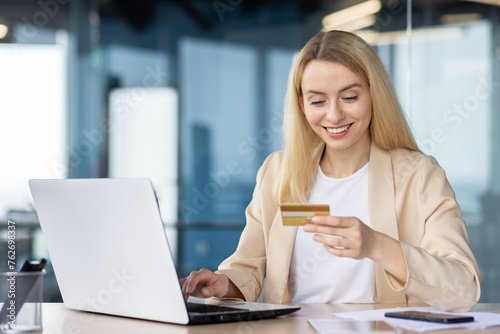 Businesswoman with credit card shopping online at office