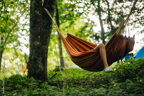 A leg hanging from a hammock in camp site in forrest.