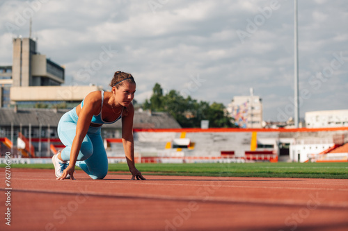 A fit sportswoman in start position on running track on stadium. © Zamrznuti tonovi