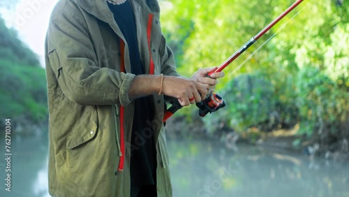 Fishing in nature with a man in a tourist robe. Men's hands hold a fishing rod. photo