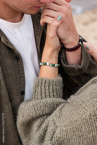 Close-up of a womans hand on a mans face  showcasing a turquoise bracelet. It evokes a sense of tender connection  and love in young age..