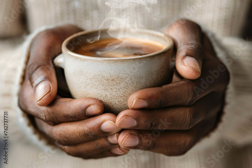 A close-up of hands holding a steaming cup of coffee