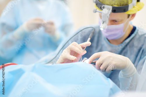 Surgeons are during maxillofacial operation using microscope and endoscope in modern hospital. Teamwork of doctors. Maxillofacial surgery. photo