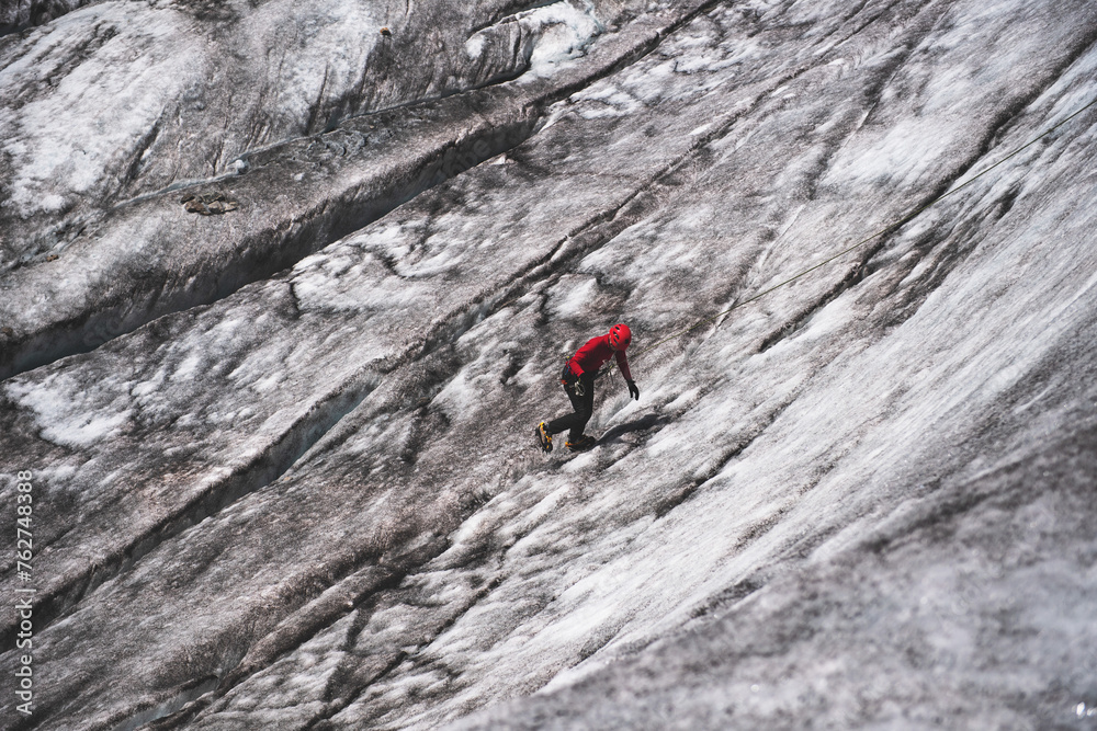 Alpinist climbing on ice wall cowered by dust on glacier Mer De Glace, Mont-Blanc massif in French Alps. Alpinist climbing on ice wall cowered by dust on glacier Mer De Glace, Mont-Blanc massif in French Alps.