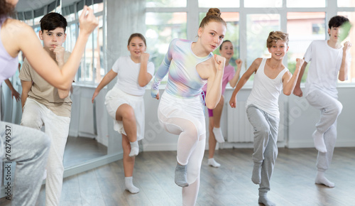 Young girls and boys repeat the movements of dance teacher, training in a spacious studio