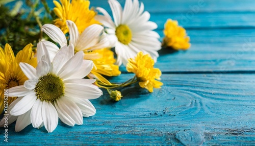 floral arrangement of white daisies and yellow flowers scattered on a vibrant blue wooden background