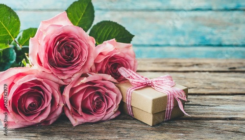 pink roses with gift box over weathered wooden planks for mothers day holiday concept background