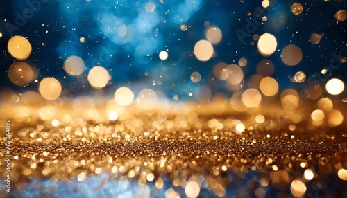 abstract festive background with shimmering gold particles and twinkling lights and bokeh effect on a blue background
