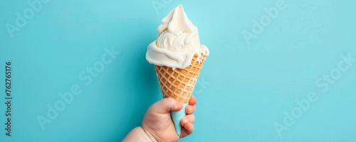 Baby kid hand holding big ice cream in waffles cone on blue background