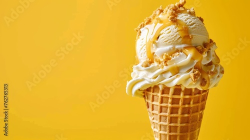 Caramel ice cream in waffles cone with caramel toppings on yellow background