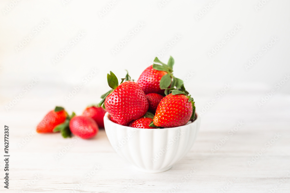 Fresh strawberries in a bowl on white wooden background. Top view with space. Nature fruit concept and healty eating. Fresh strawberries in a bowl on white wooden background. Top view with space. Nature fruit concept and healty eating.